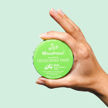 Australian-made Woohoo WILD Vegan Deodorant Paste 60g held in a hand on a light green background
