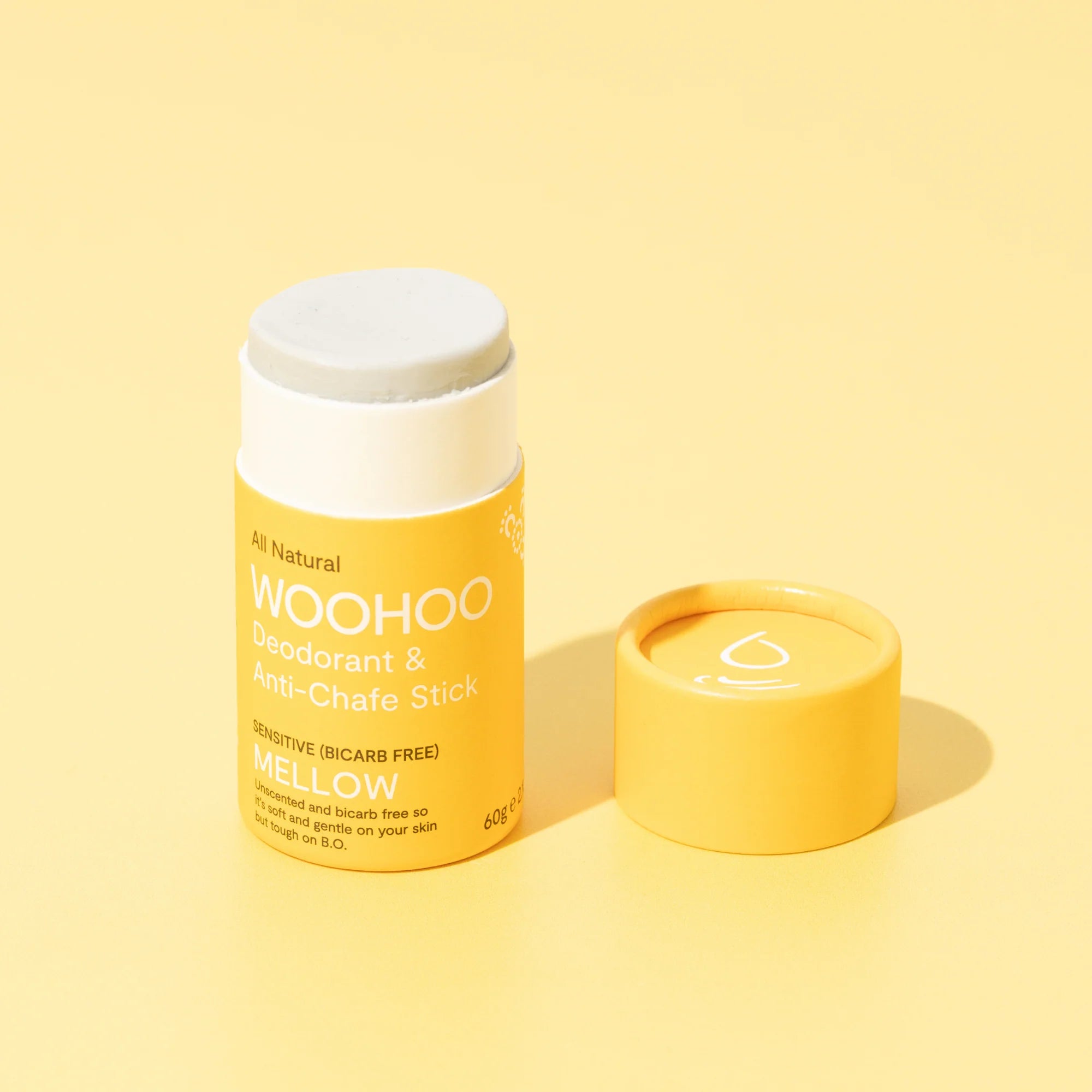 Image of opened Mellow Natural Bicarb-free Deodorant Stick with cardboard cap next to the product on a light yellow background