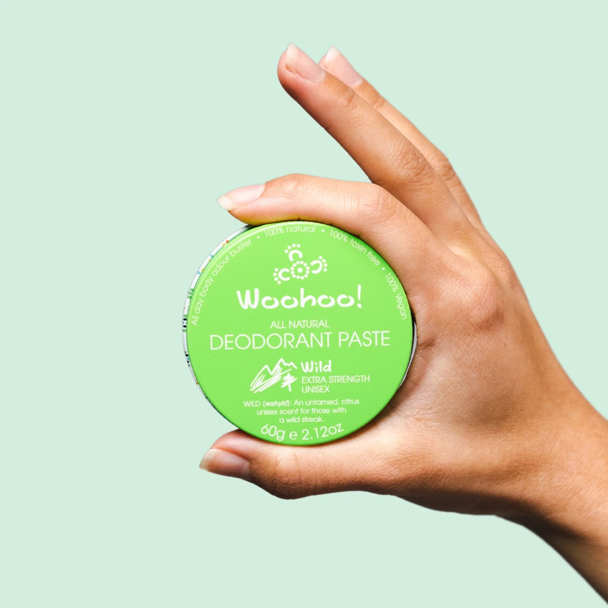 Image of the Woohoo Wild Natural Deodorant Paste tin being held in a hand on a light green background