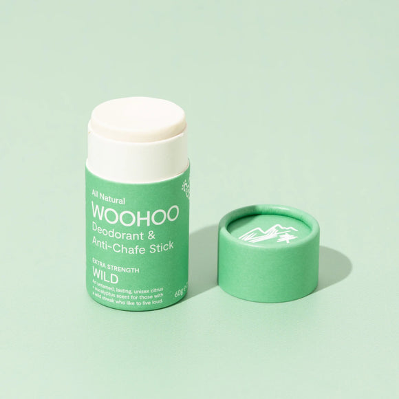 Image of opened Wild Natural Deodorant Stick with cardboard cap next to the product on a light green background