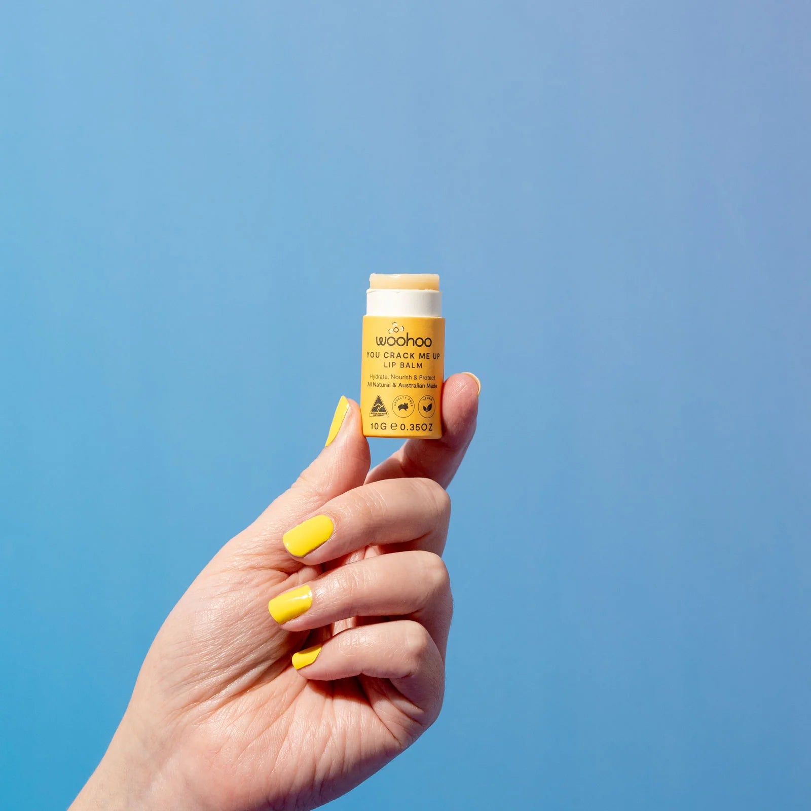 Image of an opened Woohoo You Crack Me Up! Lip Balm being held in a hand on a blue background