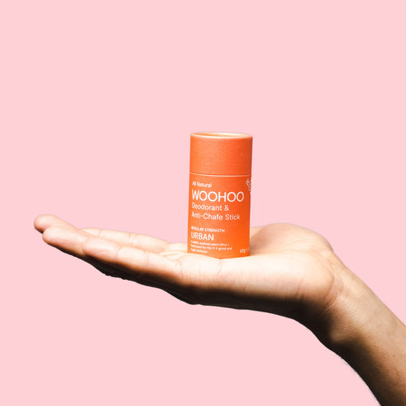 Image of Woohoo URBAN Natural Deodorant Stick 60g sitting on the palm of a hand with a pink background